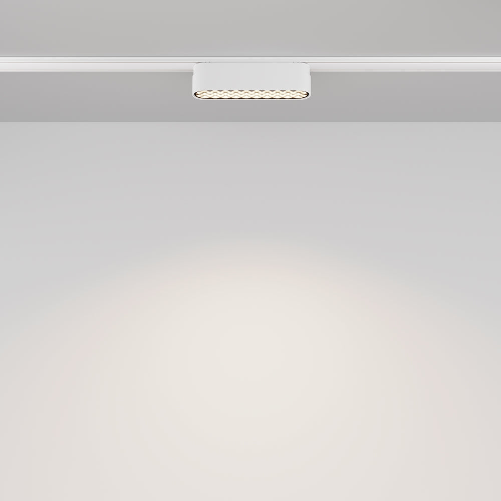 Vue frontale du projecteur sur rail, halo lumineux diffusé sur la surface claire.
