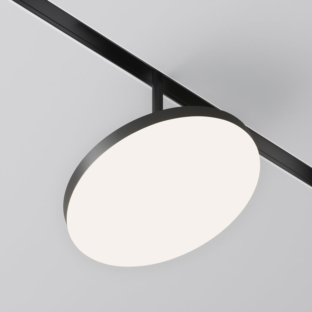 Spot rond noir suspendu sous un rail de plafond, diffuseur blanc allumé
