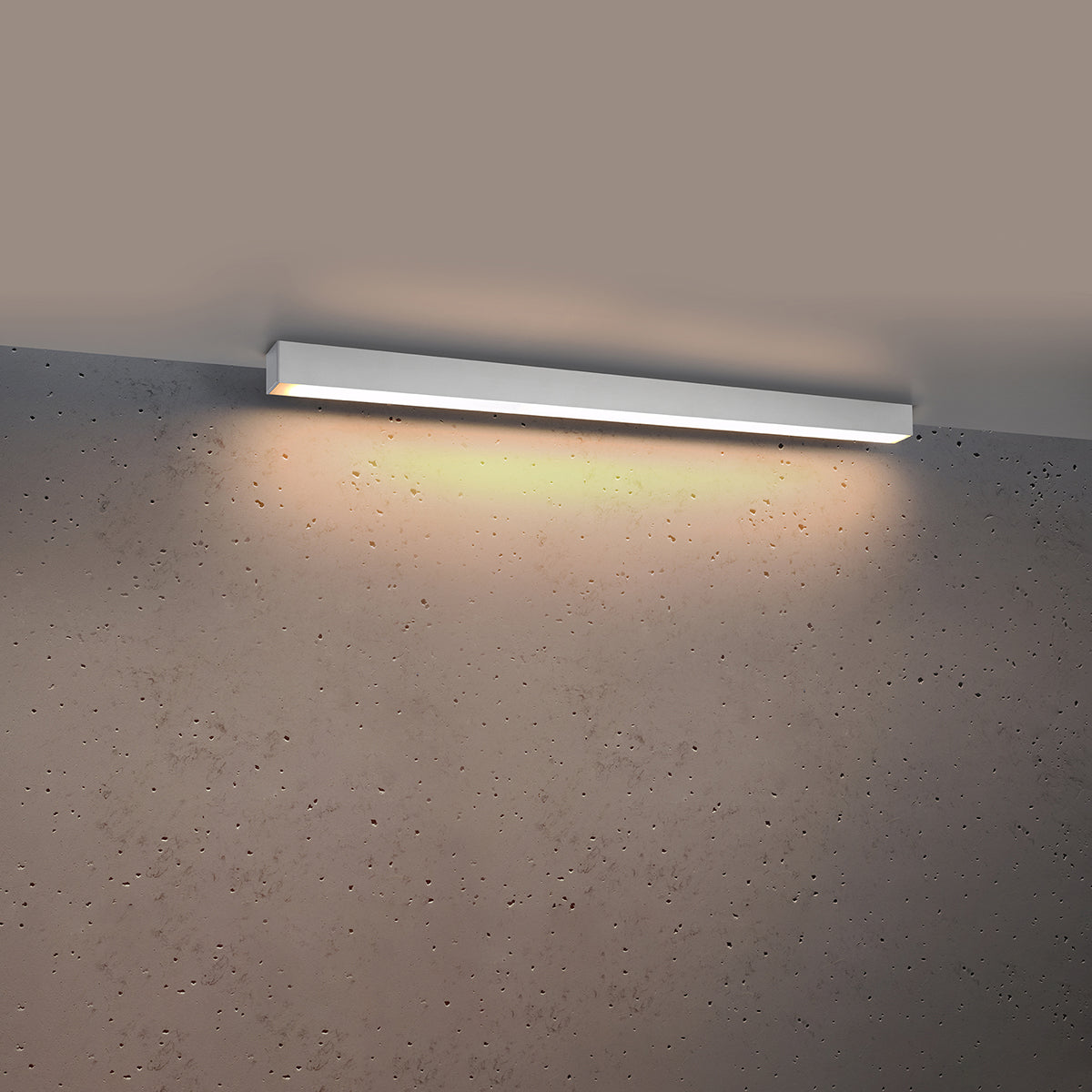 Même plafonnier allumé diffusant une lumière chaude en halo sur le mur gris