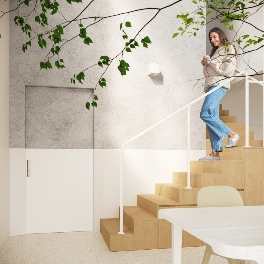 Mise en situation dans un escalier, femme souriante, applique allumée sur mur