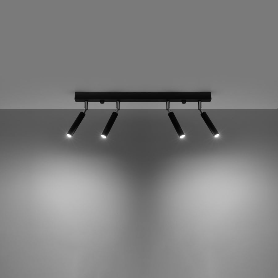 Plafonnier allumé éclairant un mur gris avec quatre faisceaux lumineux orientables