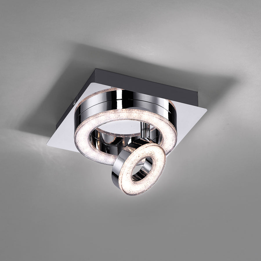 Plafonnier chromé allumé, fixé au plafond, diffusant une lumière LED chaude
