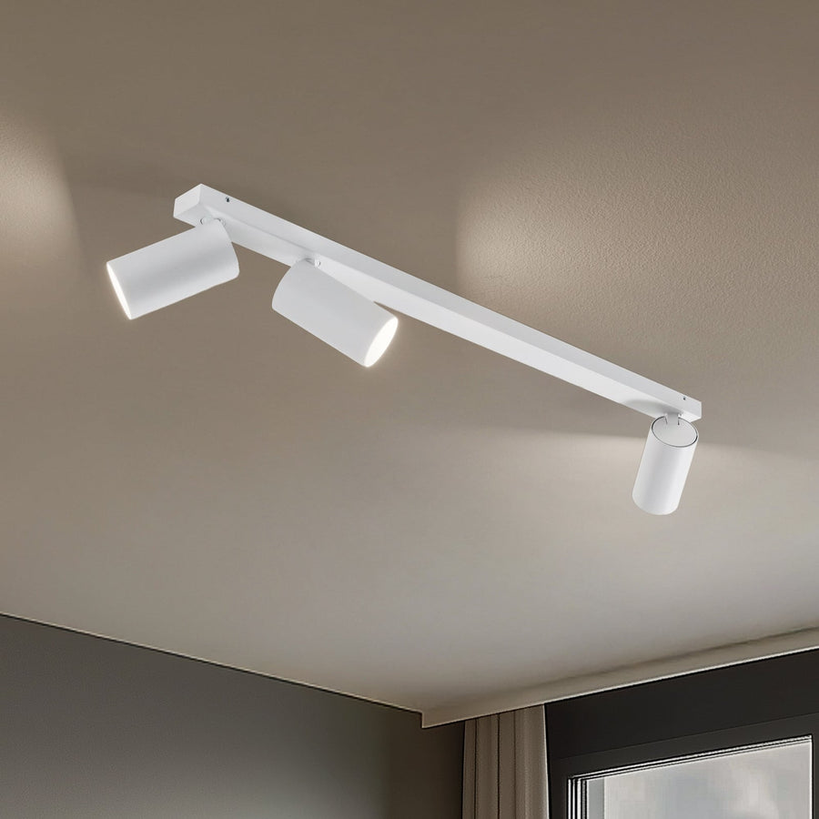 Vue rapprochée du luminaire blanc à trois spots cylindriques fixé au plafond, lumières allumées.
