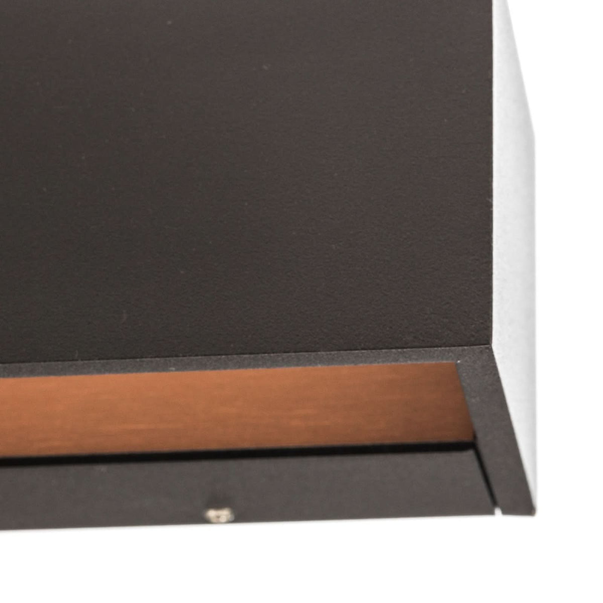 Détail de coin sur fond blanc, bord noir mat et bande cuivrée de la finition.