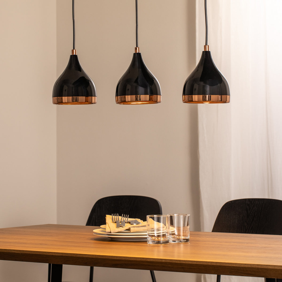 Suspension triple au-dessus d'une table en bois dressée avec assiettes et verres