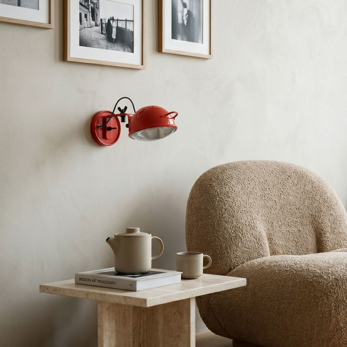 Mise en ambiance avec l'applique rouge au-dessus d'une table et d'un fauteuil bouclé.
