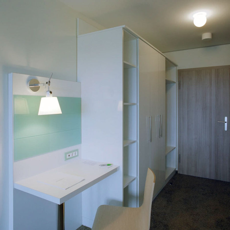 Vue d’ensemble du coin bureau blanc, applique murale fixée sur un panneau vert pâle.