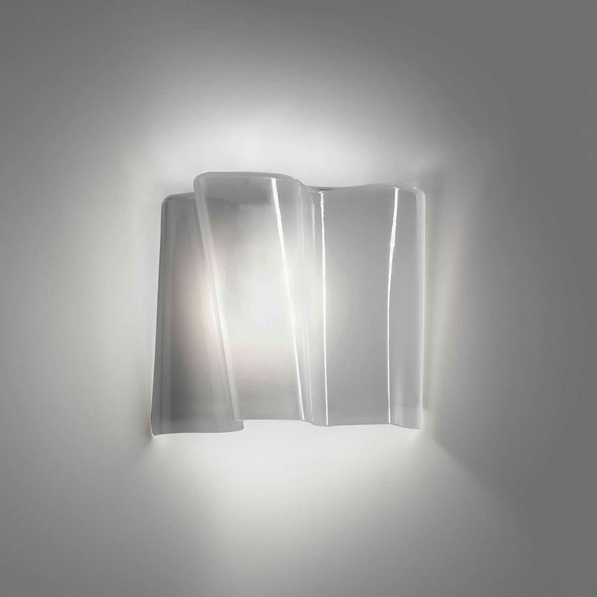 Applique murale en verre ondulé allumée, halo lumineux sur mur neutre.