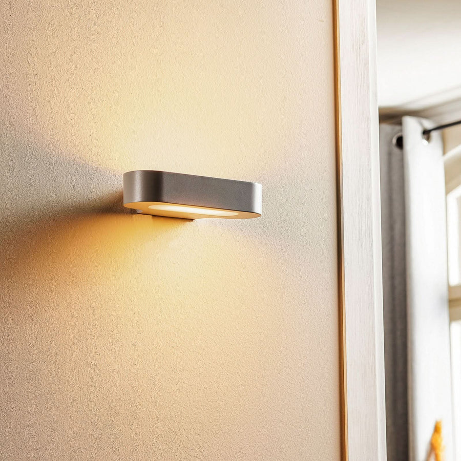 Vue de trois quarts de l'applique fixée au mur près d'une fenêtre.