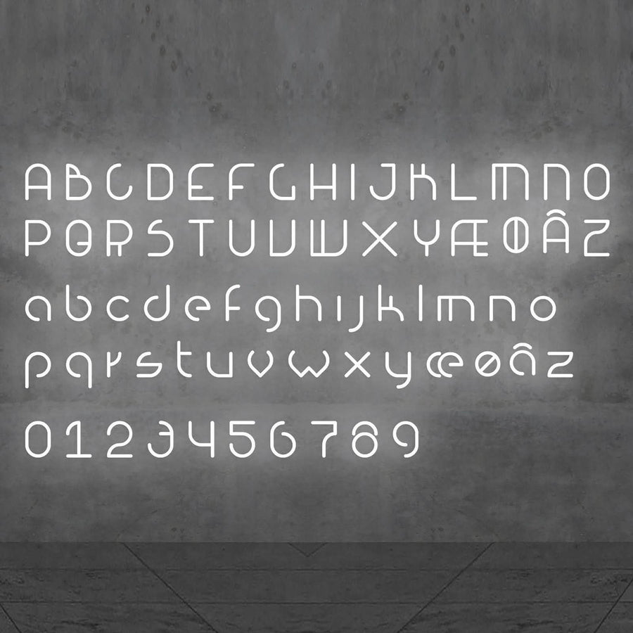 L'alphabet complet et les chiffres stylisés brillent en blanc sur un mur gris.