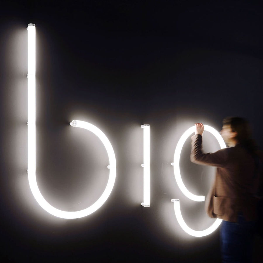 Personne installant de grandes lettres lumineuses b19 sur un mur sombre