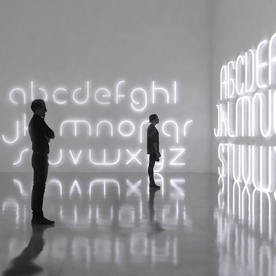 Deux personnes dans une galerie devant des lettres lumineuses géantes