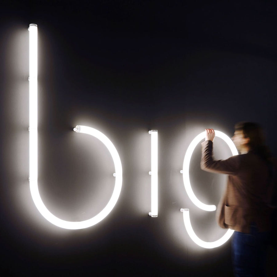 Personne ajustant les lettres b i o lumineuses sur un mur noir
