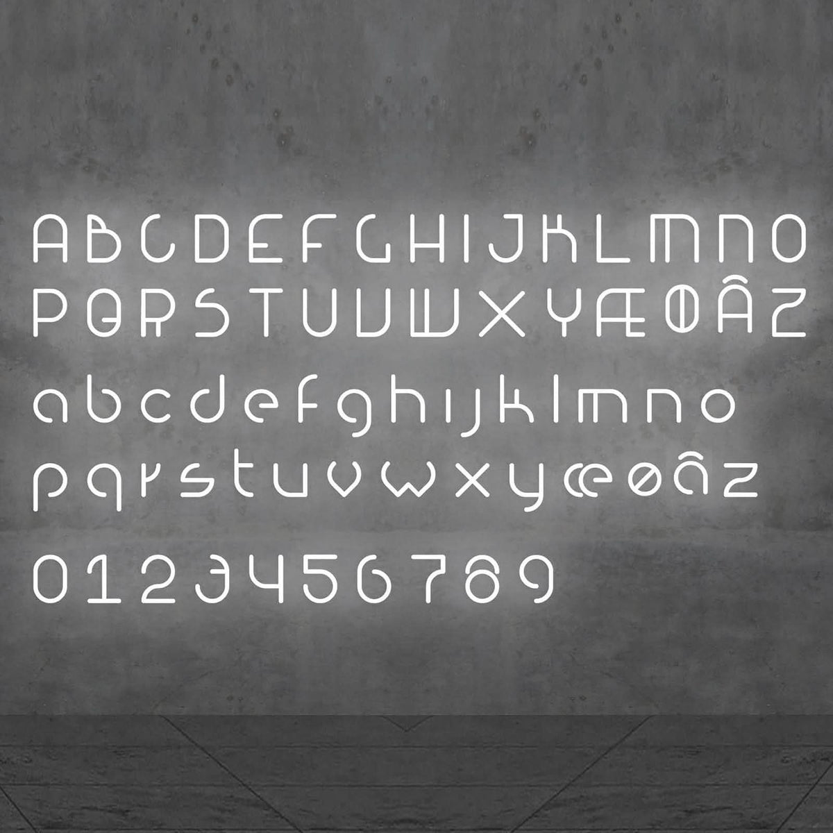 Alphabet complet et chiffres lumineux blancs présentés sur un mur gris.