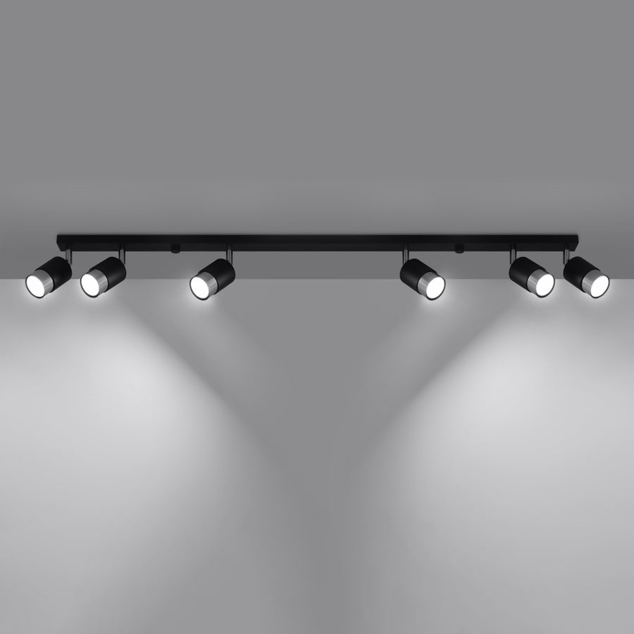 Plafonnier allumé projetant six faisceaux lumineux blancs sur une paroi grise