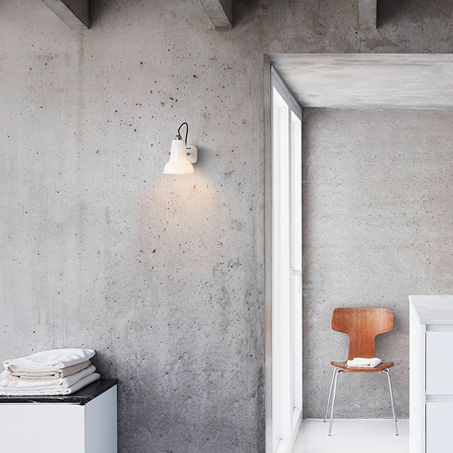 Vue d’ensemble de l’applique sur mur béton près d’une porte et d’une chaise en bois.