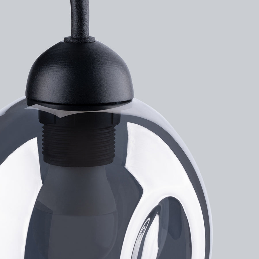 Détail rapproché du support noir et du col fileté sous l’abat-jour en verre.