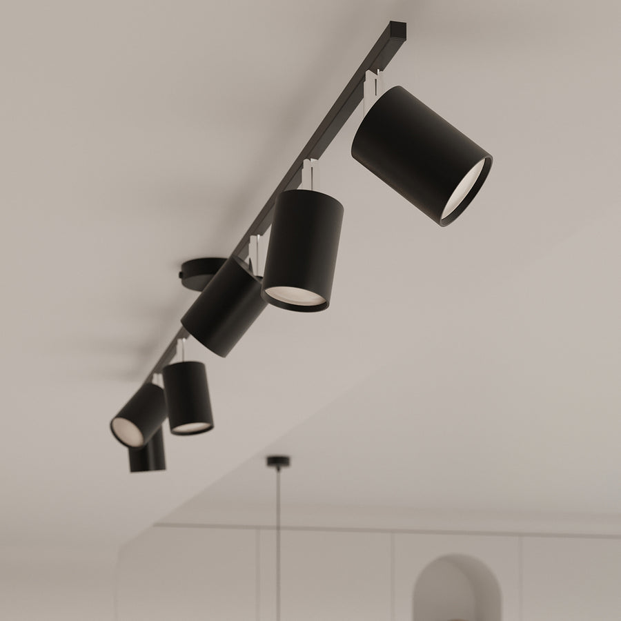 Détail en plongée des cylindres noirs orientables suspendus sous un plafond blanc