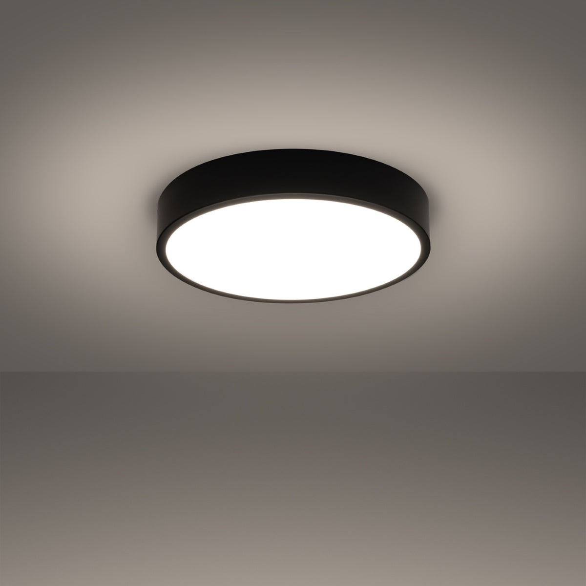 Plafonnier allumé dans une pièce sombre, halo lumineux diffusé sur le plafond