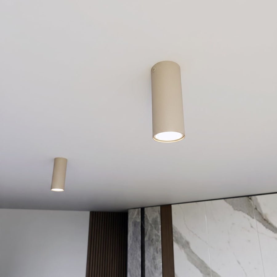 Vue en situation, deux plafonniers cylindriques beige fixés au plafond d'une pièce.