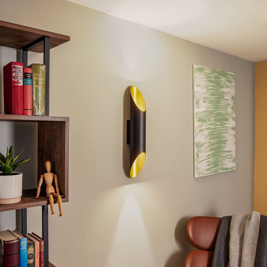 Vue d'ensemble de l'applique murale dans un salon avec étagère, livres et fauteuil.