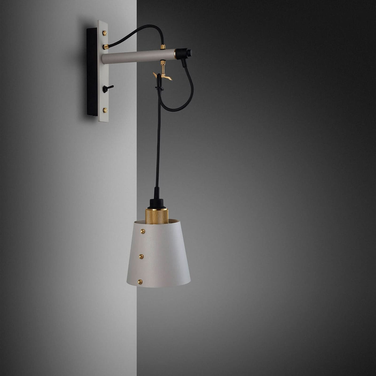 Vue de profil de l’applique fixée au mur, câble noir pendant et abat-jour conique.