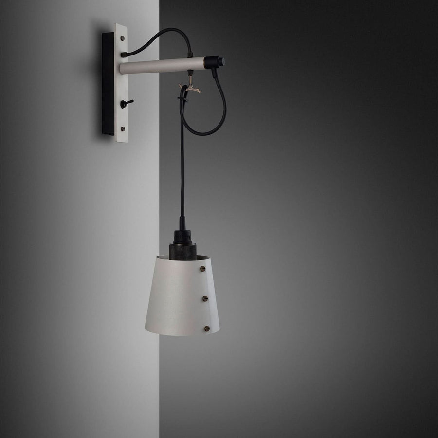 Vue de trois quarts sur mur gris, montrant la platine, le bras et le câble bouclé.