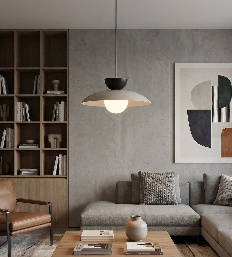 Ambiance salon : le luminaire suspendu éclaire un intérieur béton avec bibliothèque et canapé