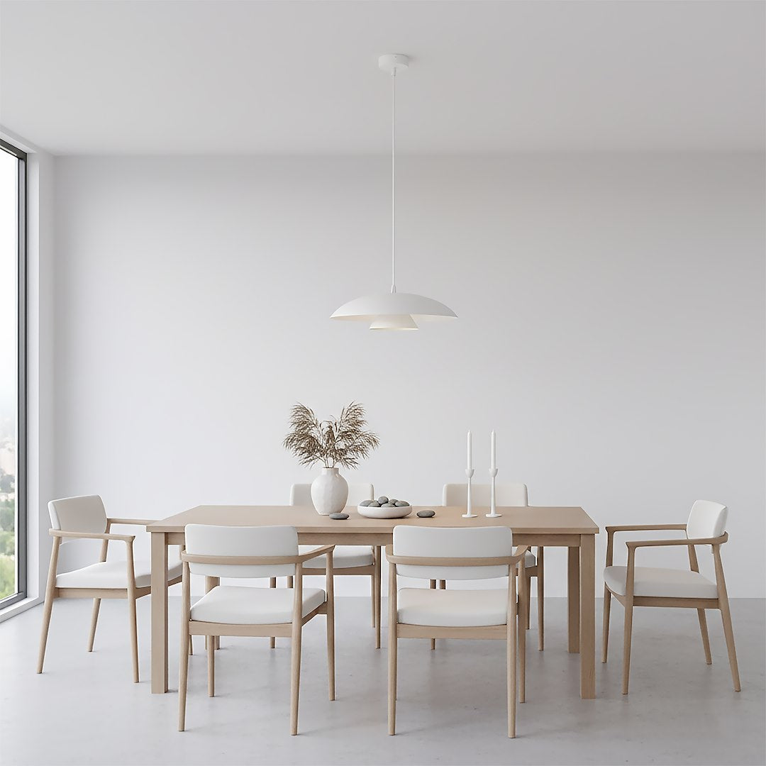 Suspension éclairée au-dessus d'une table à manger en bois clair dans un intérieur blanc