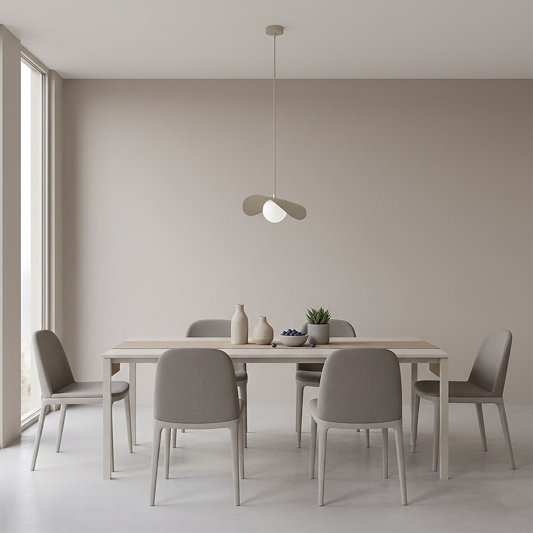 Suspension installée au-dessus d'une table à manger en bois clair, intérieur beige épuré.