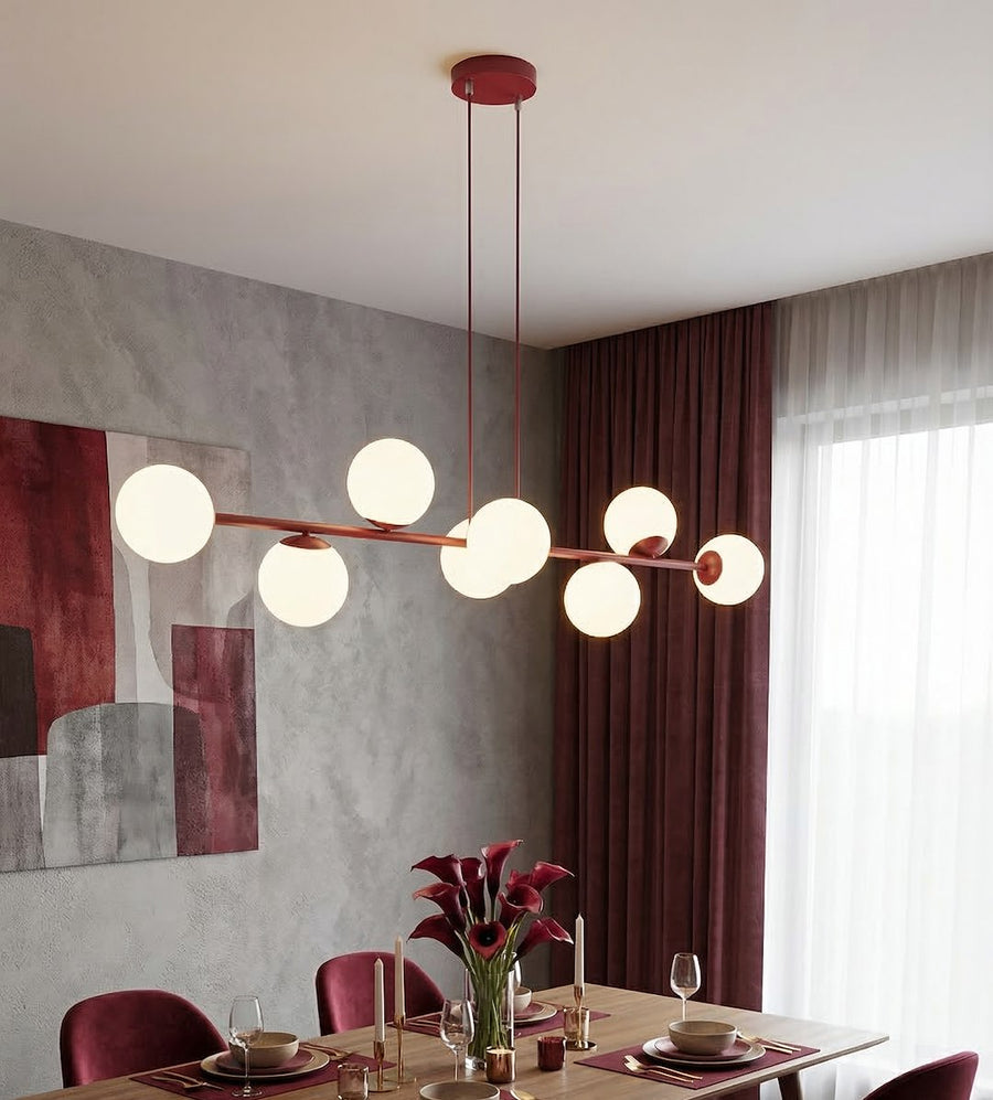 Suspension allumée au-dessus d'une table dressée dans une salle à manger aux rideaux bordeaux.