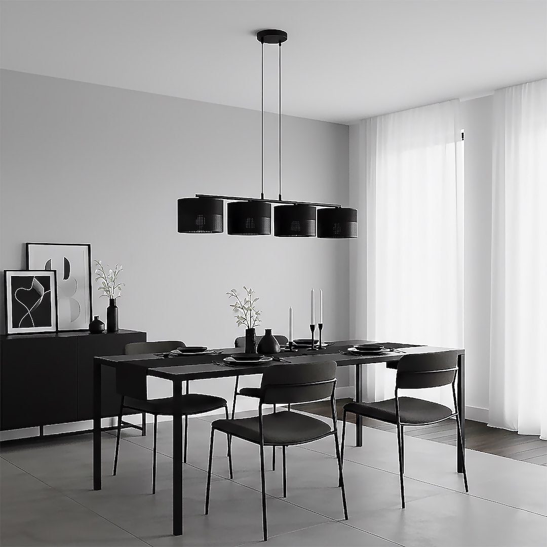 Salle à manger minimaliste noire et blanche, suspension à quatre lumières au-dessus de la table dressée.
