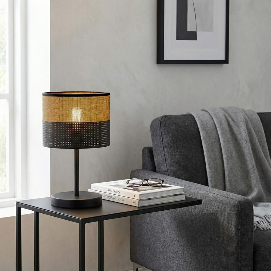Lampe posée sur table d'appoint noire, livres et lunettes à côté