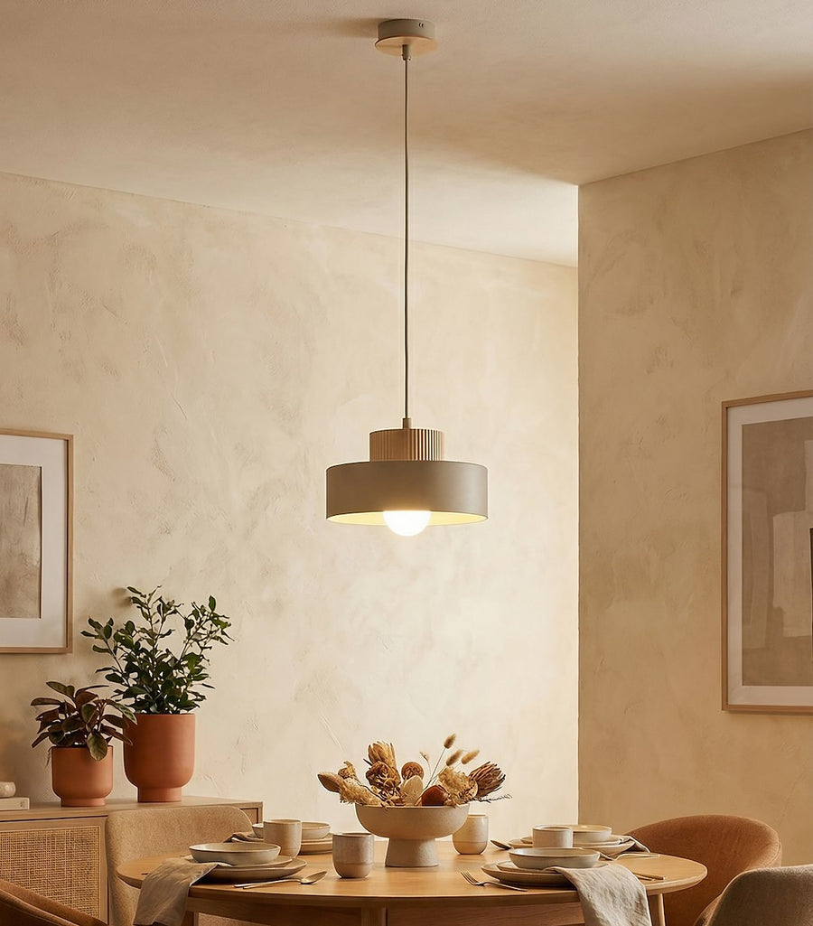 Suspension allumée au-dessus d'une table ronde dressée dans une salle à manger chaleureuse
