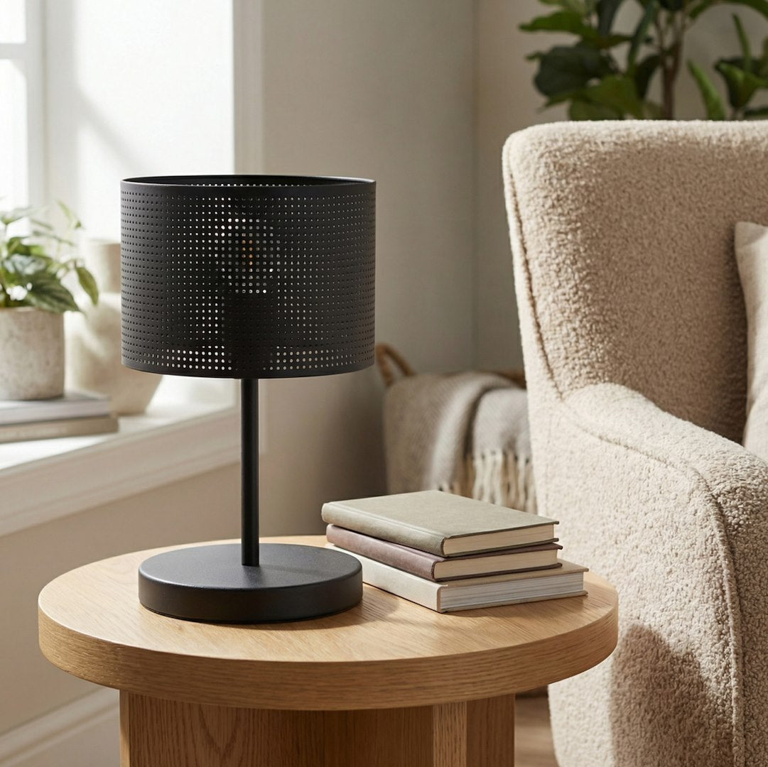 Lampe à poser noire sur guéridon en chêne, avec livres et fauteuil en bouclette.
