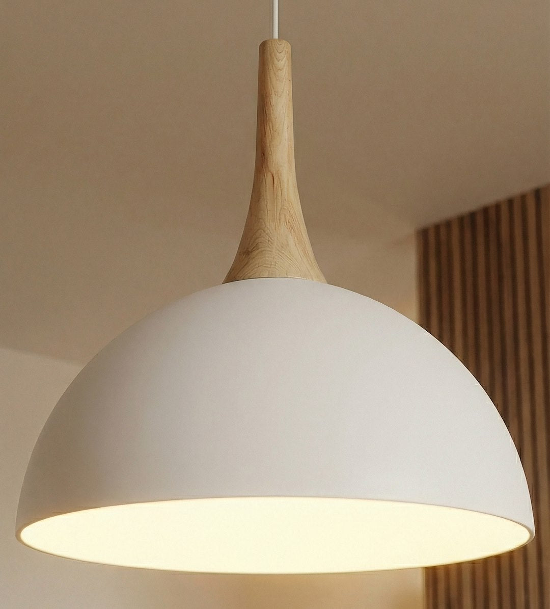 Gros plan sur l'abat-jour blanc, le col en bois et la lumière chaude.