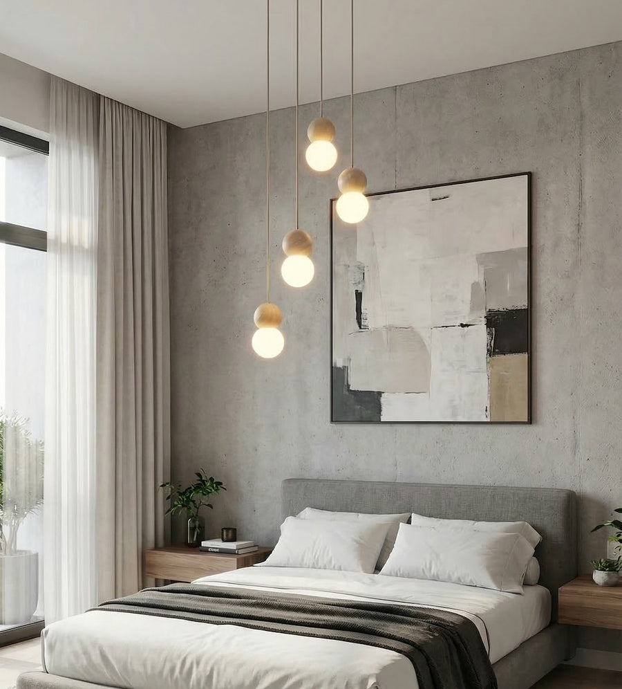 Suspension allumée dans une chambre, tête de lit grise et tableau abstrait