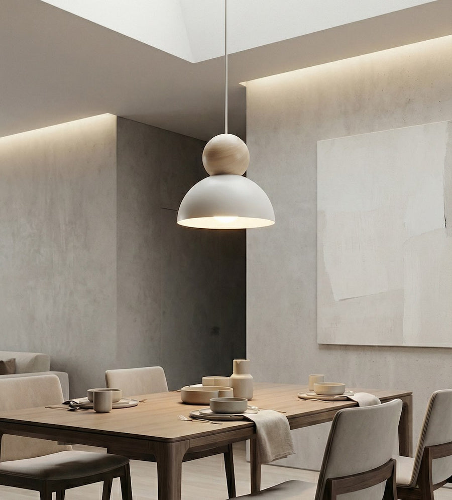 Salle à manger contemporaine, suspension allumée au-dessus d'une table en bois clair