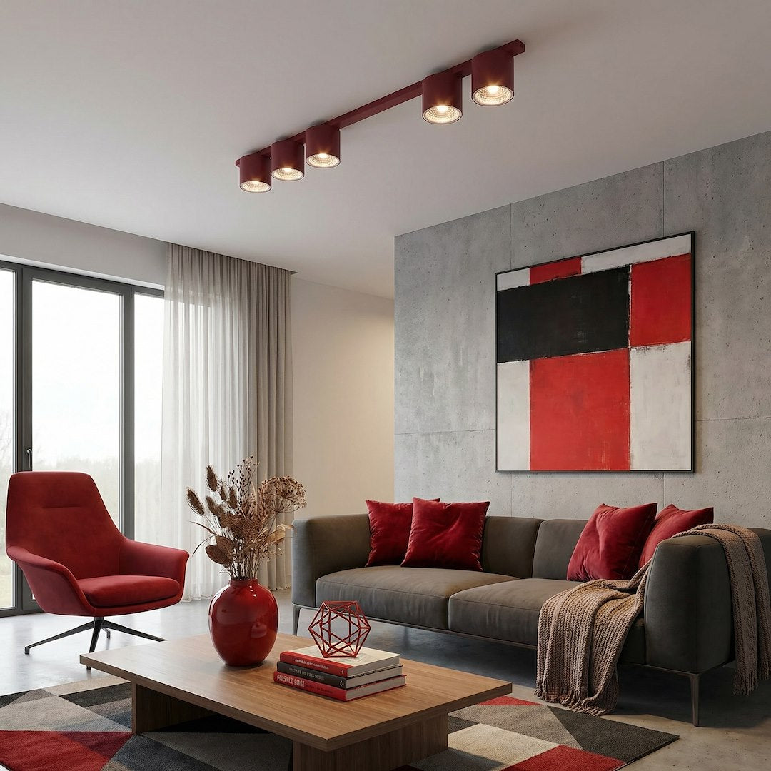 Mise en ambiance salon moderne avec fauteuil rouge, canapé gris et tableau abstrait.