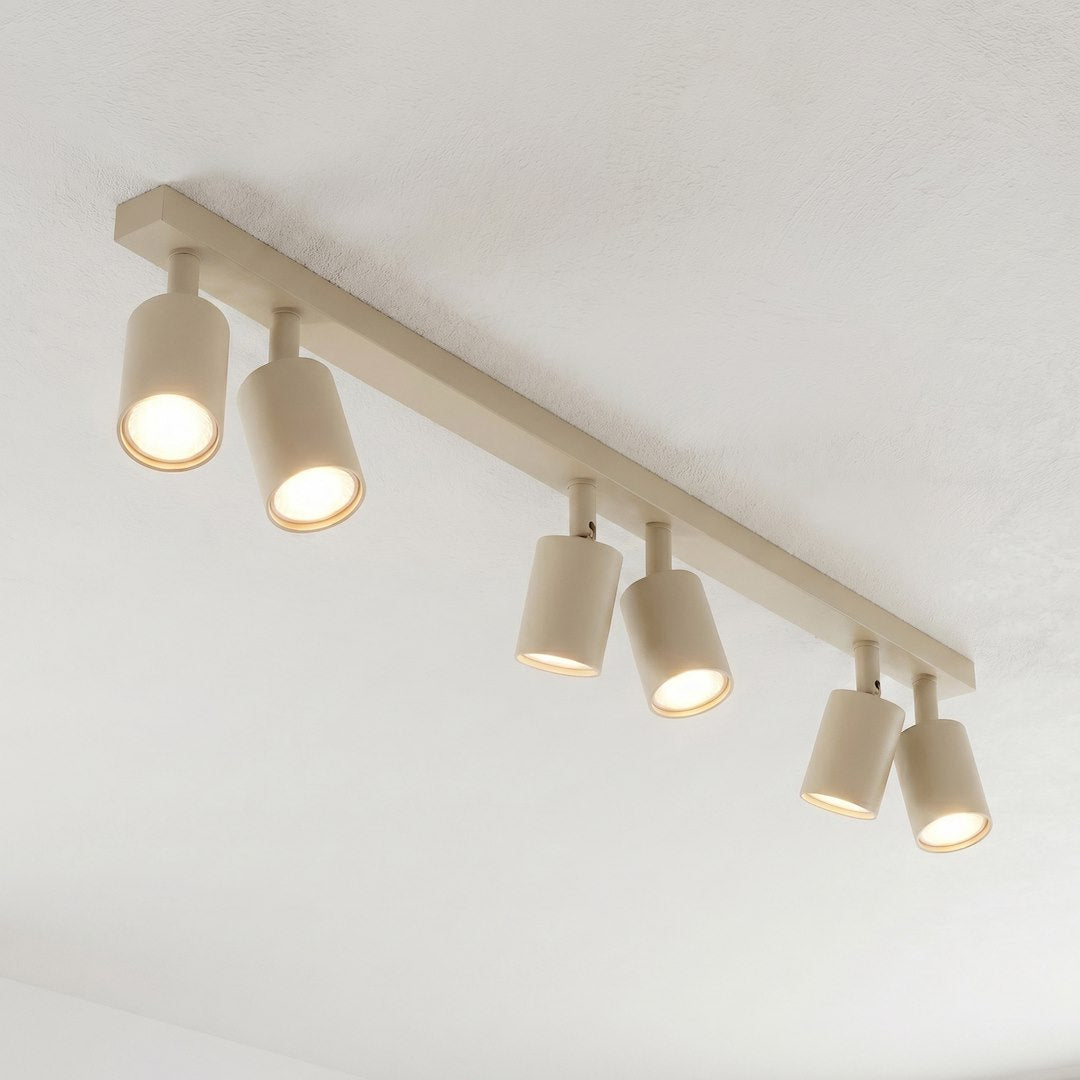 Détail rapproché des spots allumés, finition beige mate et diffuseur lumineux
