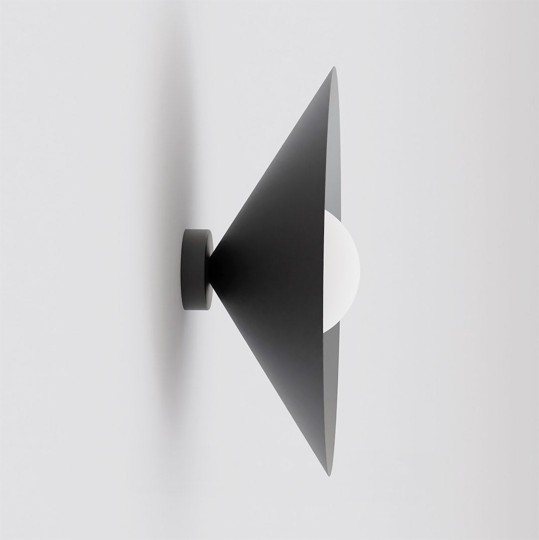 Vue de profil du cône noir et de la sphère blanche sur un mur clair