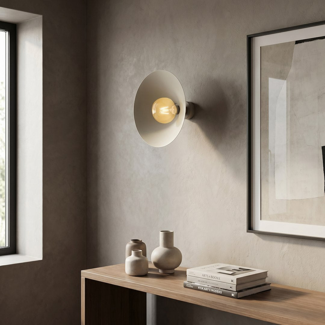 Mise en scène de l’applique beige allumée dans un intérieur minimaliste avec cadres.