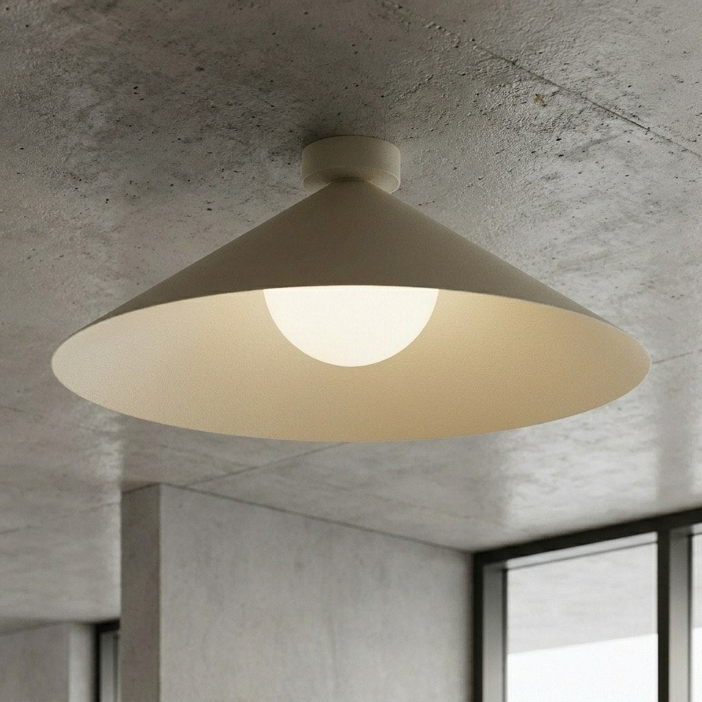Gros plan sous plafond béton brut montrant la finition beige mate et la lumière chaude.
