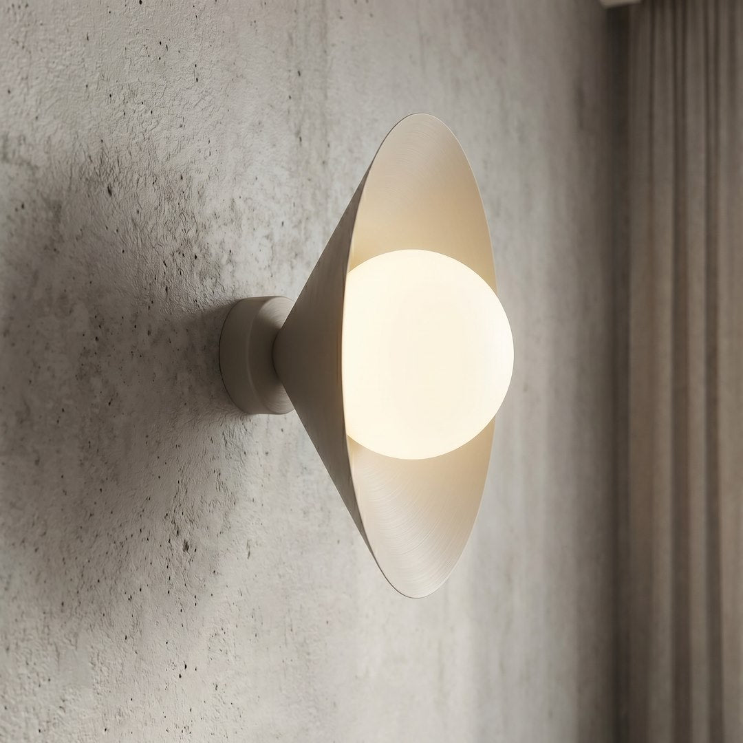 Détail rapproché de la sphère en verre blanc éclairée et du cône beige.