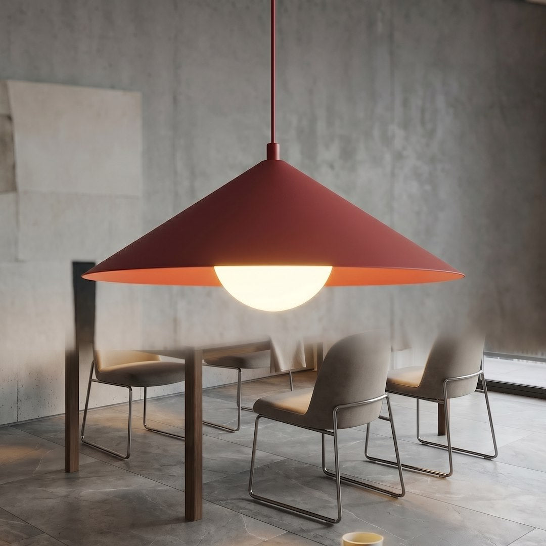 Mise en ambiance au-dessus d'une table, suspension bordeaux allumée dans un intérieur béton