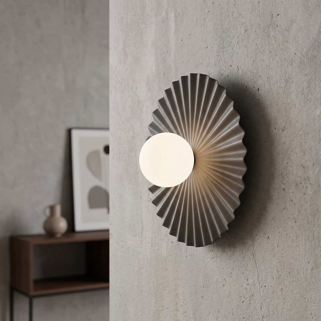 Mise en ambiance sur un mur béton, applique allumée au-dessus d'un meuble en bois.