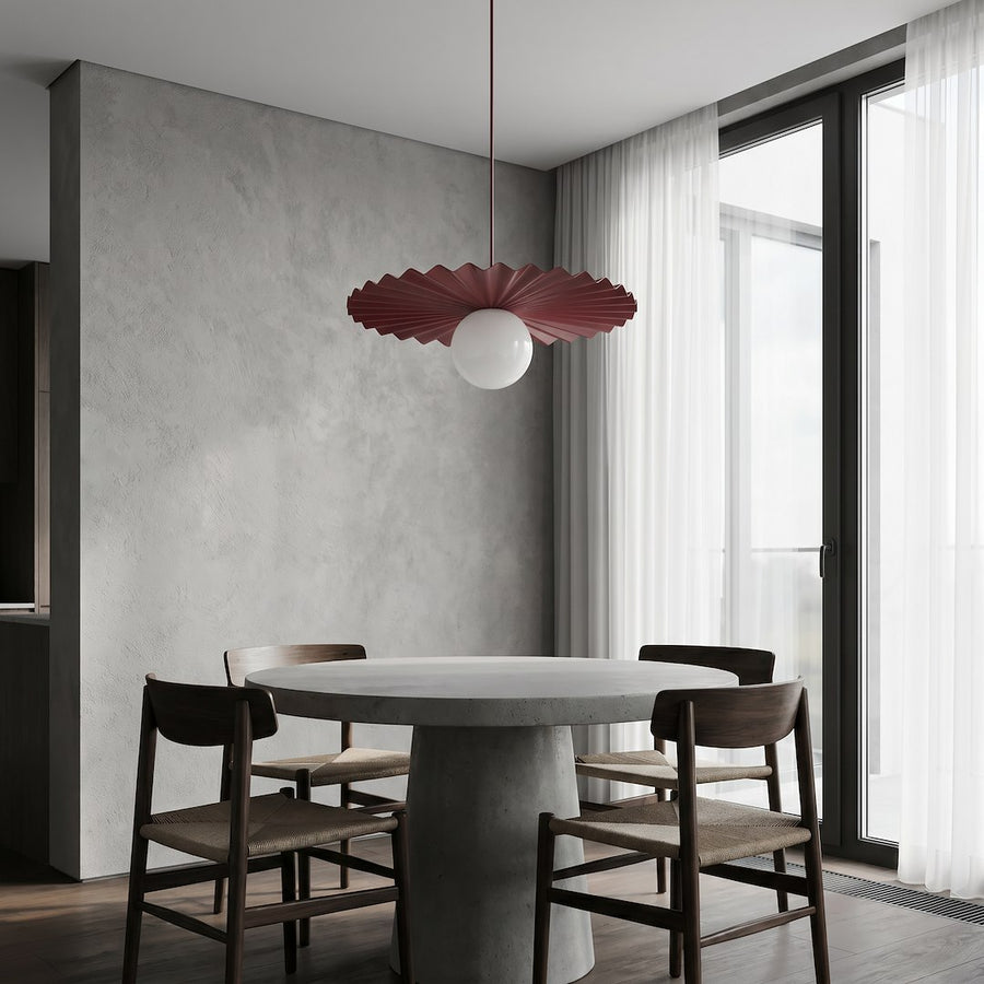 Suspension rouge bordeaux au-dessus d'une table en béton, intérieur épuré et lumineux.