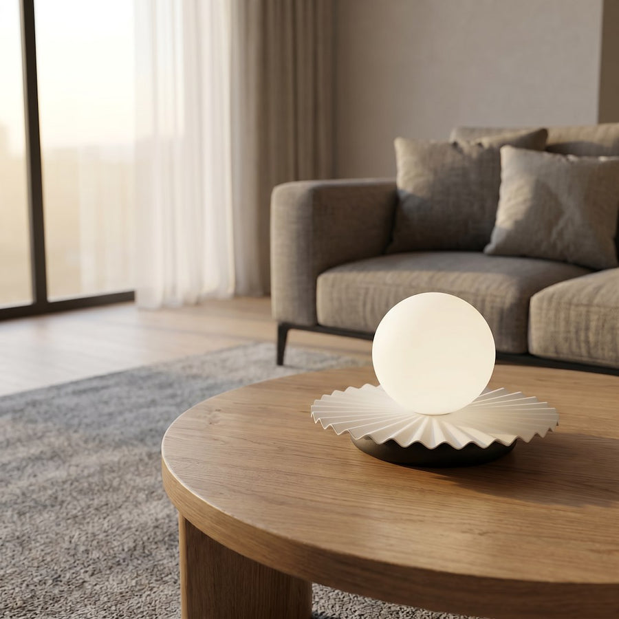 Gros plan de la lampe allumée sur table ronde en bois clair, intérieur lumineux.