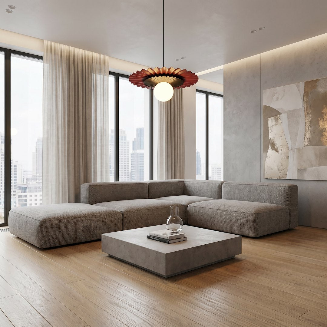 Mise en ambiance dans un salon moderne avec canapé gris, fenêtres et suspension allumée.
