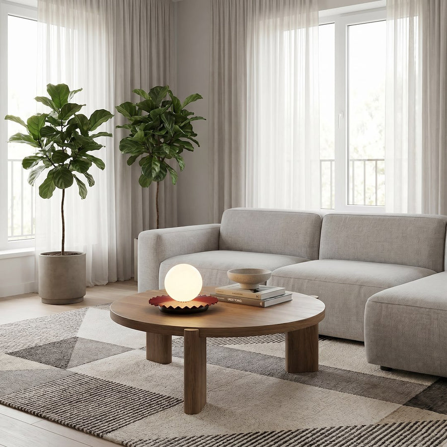 Mise en ambiance salon clair, lampe posée sur table basse entre deux plantes vertes